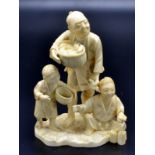 A Japanese ivory okimono, a father and two children gathering produce,