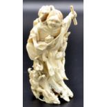 A Japanese ivory okimono of Sennin Gama dressed in ragged and torn robes standing and bending