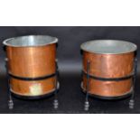 Two copper cylindrical log bins, each with black painted iron stand, each diameter 45.5cm.