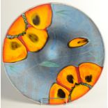 A Poole Pottery charger, the blue ground decorated with red and orange stylised flowers,