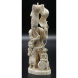 A Japanese walrus ivory figure group of a street entertainer and a youth assistant,