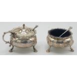 A silver Mappin & Webb mustard pot standing on three shell capped legs with hoof feet and a
