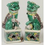 A pair of Chinese famille verte dogs of fo, seated on a floral decorated plinth base, height 14.5cm.