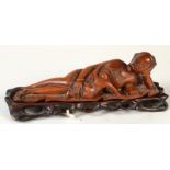 A Chinese hardwood carving of a reclining lady and child lying upon a large banana leaf,
