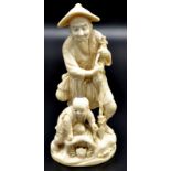 A Japanese ivory okimono, a fisherman standing upon a rock relaxing and supported by his harpoon,