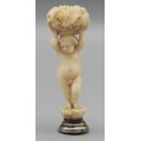 An ivory seal carved as a naked child, holding aloft a basket of grapes, height 7.7cm.