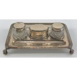 An Edwardian silver ink stand with a pair of silver mounted cut glass wells and a central oval box