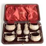 A six piece embossed silver, late Victorian cruet, cased, with three salt spoons.