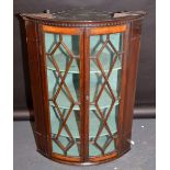 An oak hanging corner cupboard with two lattice glazed doors.