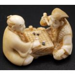 A Japanese ivory netsuke, two gentlemen seated at a game board playing "Go",
