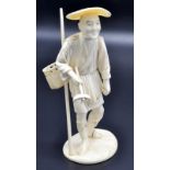 A Japanese ivory okimono of sectional workmanship carved as a standing farmer holding a trident