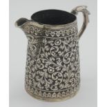 An Indian silver floral repousse decorated jug, inscribed to the base 'Ethel Mary Mountfort,
