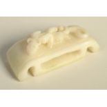 A Chinese white jade rectangular bodied belt slide with under turned ends supporting the slide,