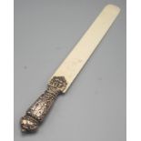 A late Victorian ivory paper knife with ornate filled silver handle by William Comyns.
