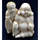 A Japanese ivory okimono, a seated Hotei holding a sacred pearl,