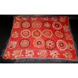 An Uzbek red ground Suzani textile, decorated with four rows of three circular medallions,