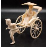 A Japanese ivory okimono, a man running and pulling a two wheeled sampan with a folded hood,