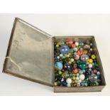 A collection of glass marbles in an old biscuit tin.