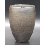 A small ovoid beaker by Margaret Way with black matt opaque glaze and a slight golden metallic