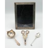 A silver mounted photograph frame, a silver tea strainer,