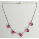 A silver necklace set five faceted pink stones.