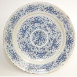 A large Delft pottery blue and white charger, decorated with panels containing stylised flowers,