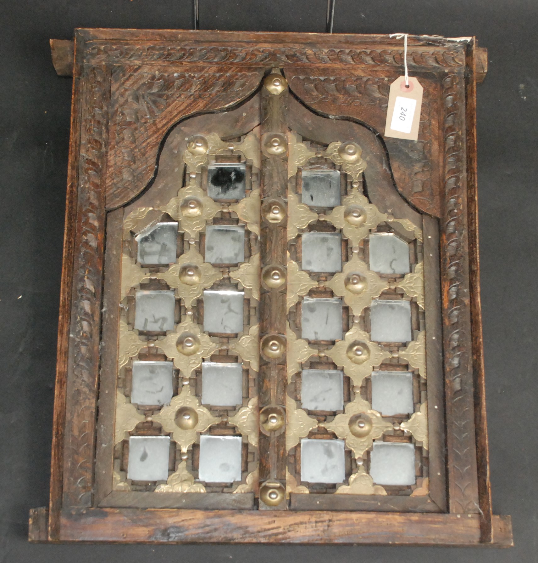 An Indian carved hardwood and brass mounted wall mirror.