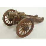 A model of a brass cannon, on a wooden and brass carriage, total length 21.5cm, height 10.5cm.
