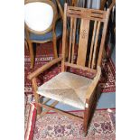An early 20th century Arts and Crafts oak rocking chair with a seagrass seat,