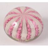 A latticino glass paperweight, decorated with pink spiral twist ribbons, diameter 9cm.