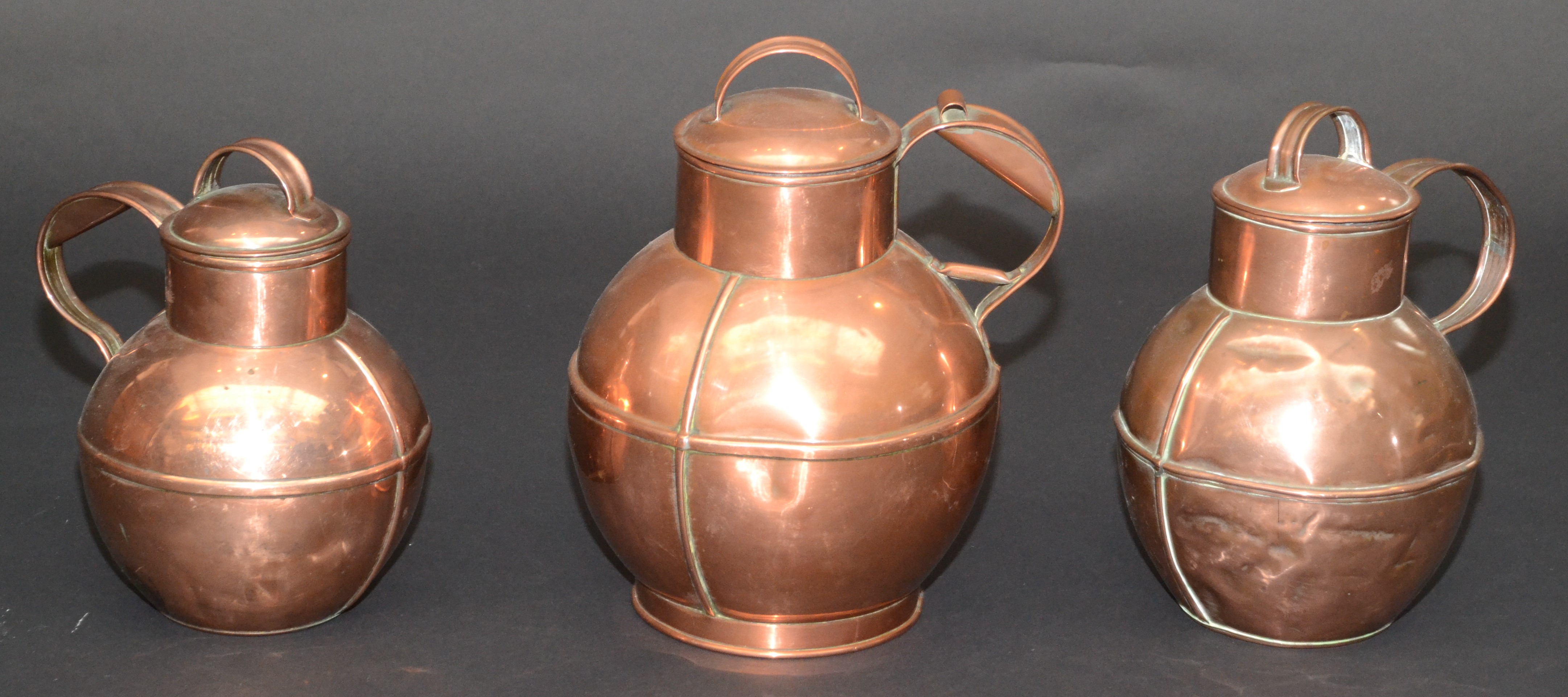 Three Jersey copper graduated jugs and covers, early 20th century,