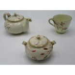 A Belleek porcelain teapot, sugar bowl and cup, enamelled with floral sprays, in pink and iron red,