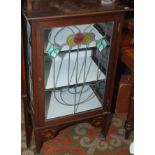 An Art Nouveau low display cabinet, the glazed door with leaded coloured glass.