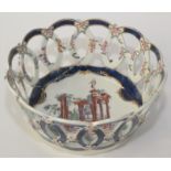 An 18th century Worcester porcelain basket painted with classical ruins and figures to the centre,