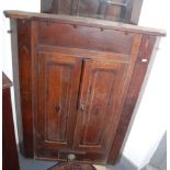 A hanging corner cupboard with blind panel doors.