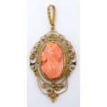 A coral cameo set in an ornate gold filigree pendant mount.