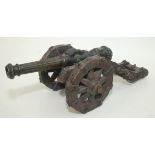 A cast metal cannon, surmounted by dolphin finials, on a wooden carriage, length of cannon 41cm,