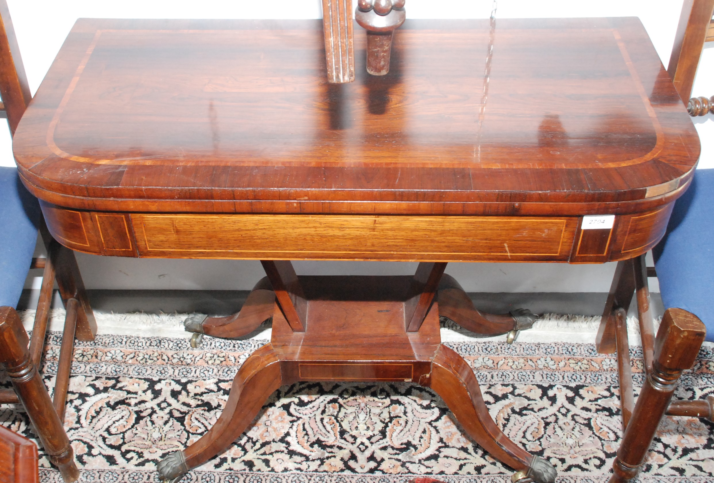 A Regency inlaid, fold top card table on four sabre legs with lions paw feet, width 91.5cm.