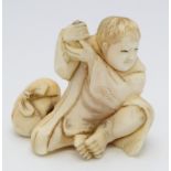 A Japanese ivory okimono, a youth seated and holding his hands at shoulder height,