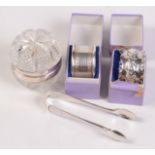 A pair of silver mounted cut glass salts, two silver napkin rings and a pair of silver sugar tongs.