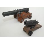 Two models of ships cannons, each mounted on a wooden carriage, lengths 27cm and 15.5cm.