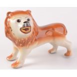 A large Staffordshire pottery figure of a lion, with glass eyes, length 33cm, height 25cm.