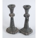 An unusual pair of Cornish serpentine candlesticks carved with bands that simulate a rocky coast,