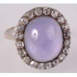 An 18ct white gold star sapphire ring the large oval cabochon within twenty diamonds.