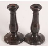 A pair of Cornish red serpentine candlesticks, each with a baluster stem and circular base,