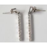 A pair of contemporary white gold earrings each with a pendant diamond set baton.