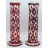 A pair of ruby flashed cut glass cylindrical vases, each decorated with stylised plants,