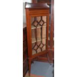 An Edwardian standing inlaid mahogany corner cabinet with lattice glazed door and splayed legs.