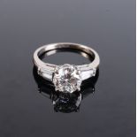 A fine and impressive solitaire diamond ring with tapered baguette cut paste shoulders,