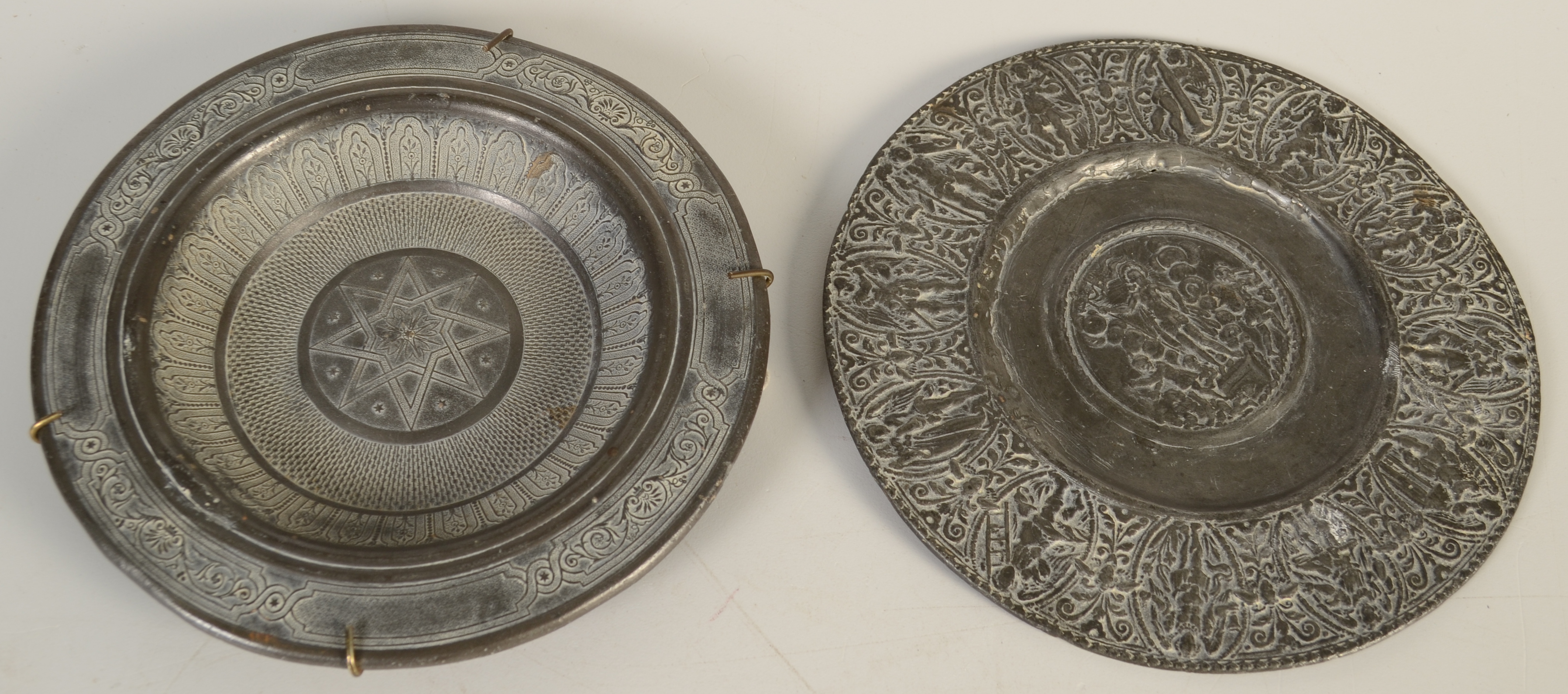 A pewter dish in 17th century style, to the centre Christ holds a flag and cross,